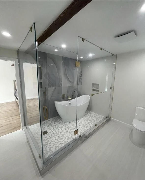 Large bathroom with freestanding tub, glass shower enclosure, gray tile and white vanity