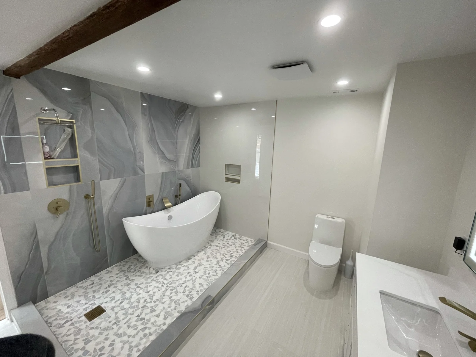 Modern bathroom with a freestanding tub, walk-in shower, large-format wall tile and brushed-gold fixtures