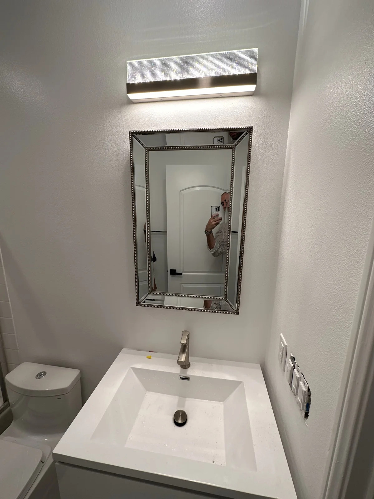 Compact bathroom vanity with framed mirror, modern sink and bathroom lighting