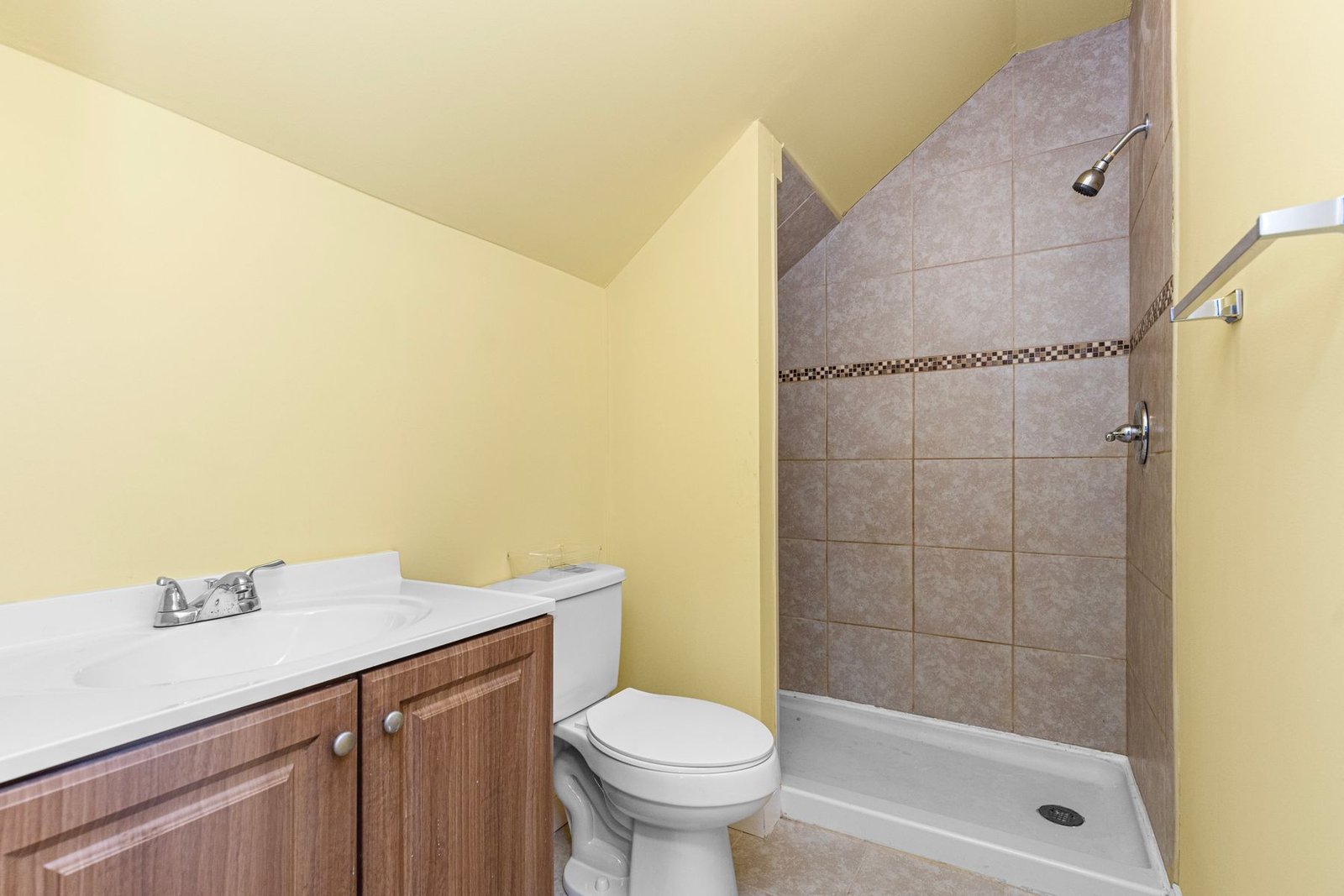 Compact bathroom with yellow walls, shower, toilet and wood vanity