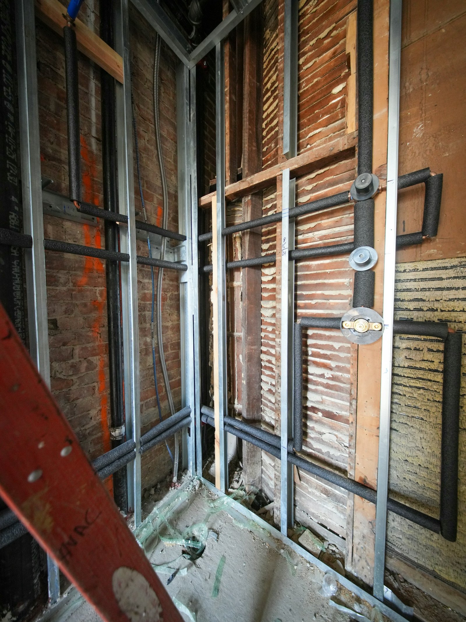 Exposed plumbing pipes inside a wall during renovation