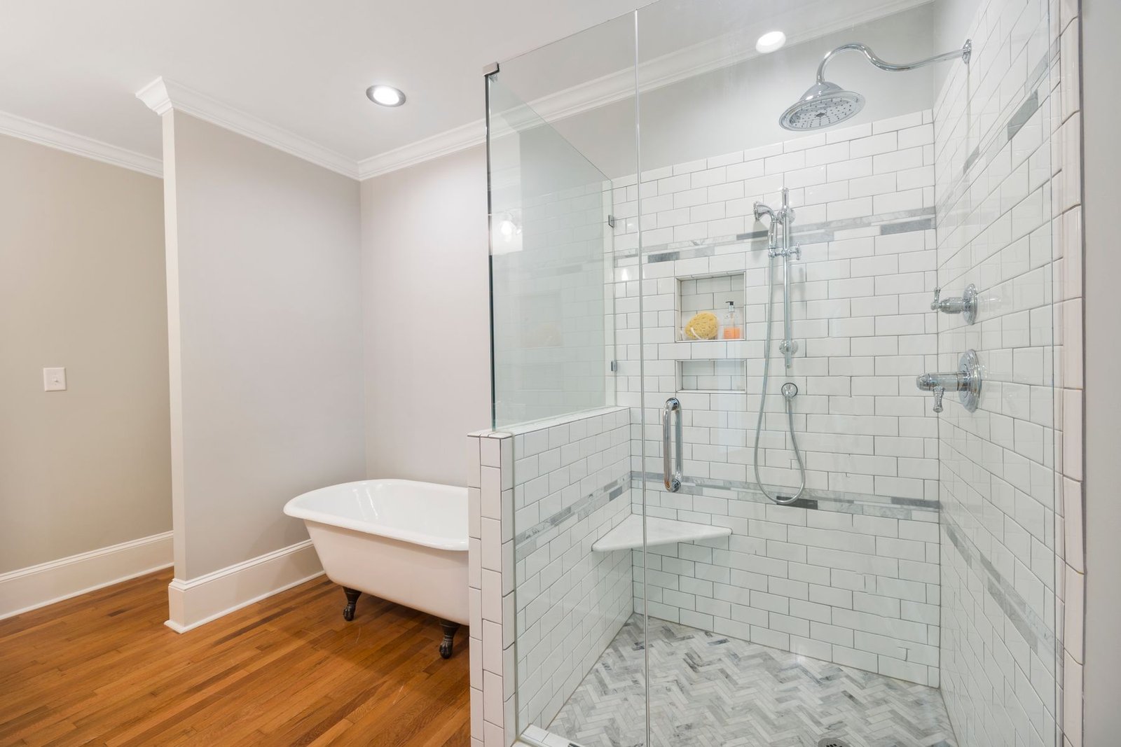 Glass shower enclosure beside a freestanding bathtub