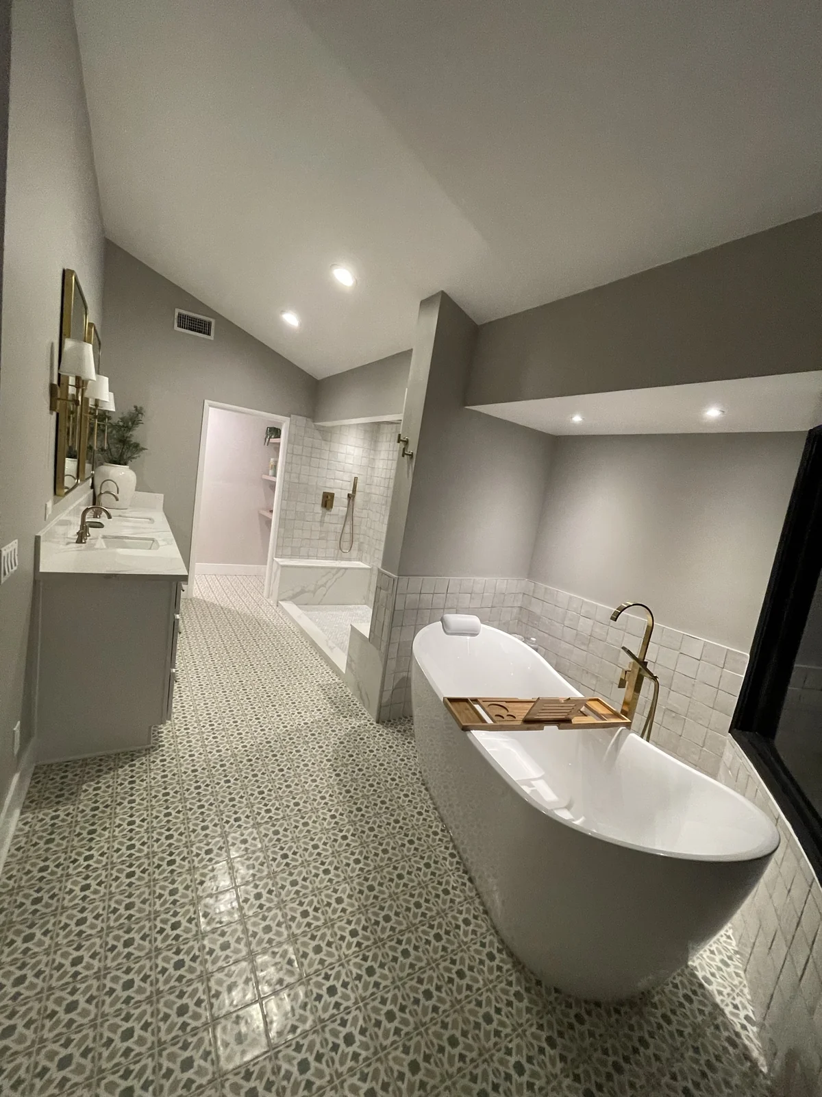 Large bathroom with freestanding tub, walk-in shower, double vanity and patterned tile floor