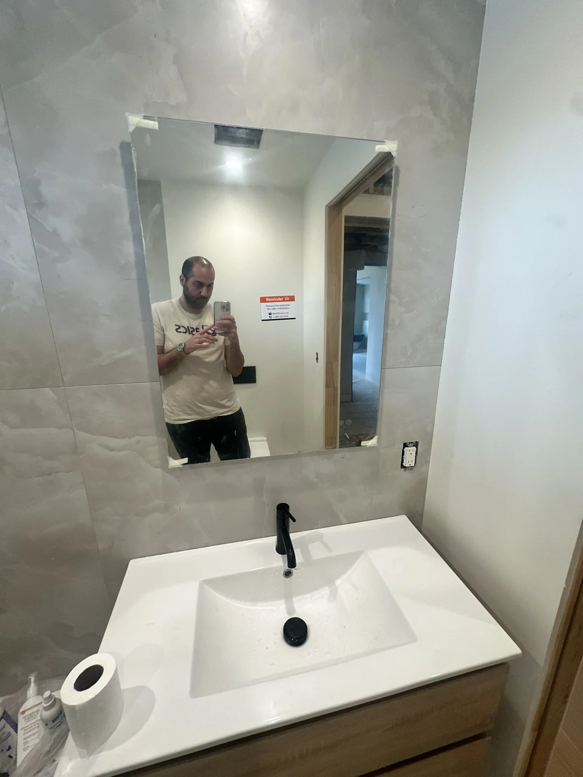 Bathroom vanity with white counter and large framed mirror during installation