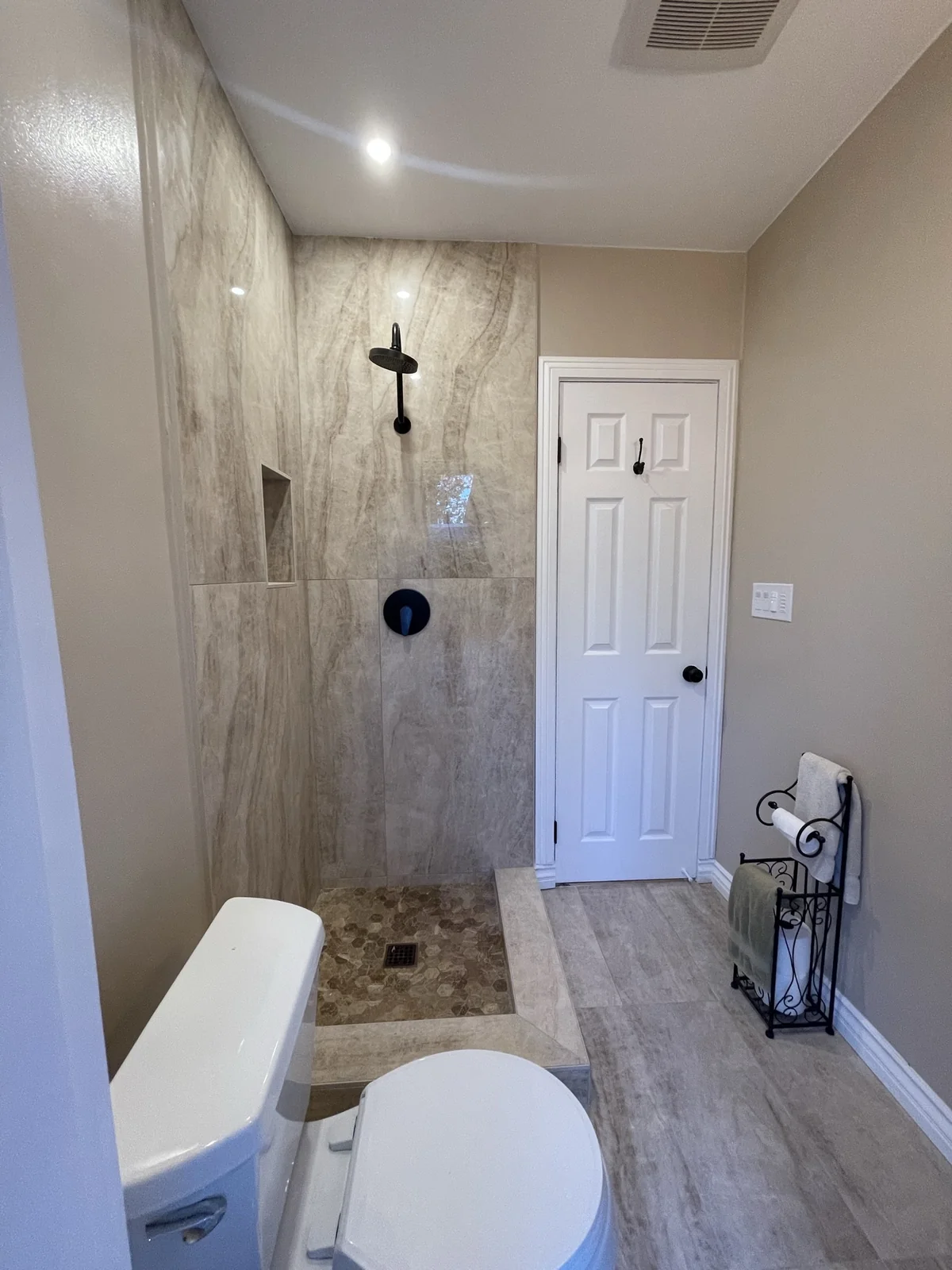 Bathroom with a low-threshold tiled shower, recessed niche and wall-mounted showerhead