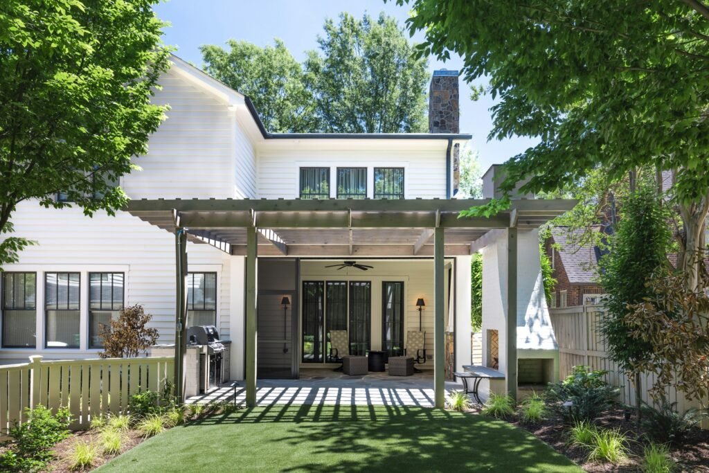 White two-story home opening onto a covered patio, planted borders and a compact lawn.