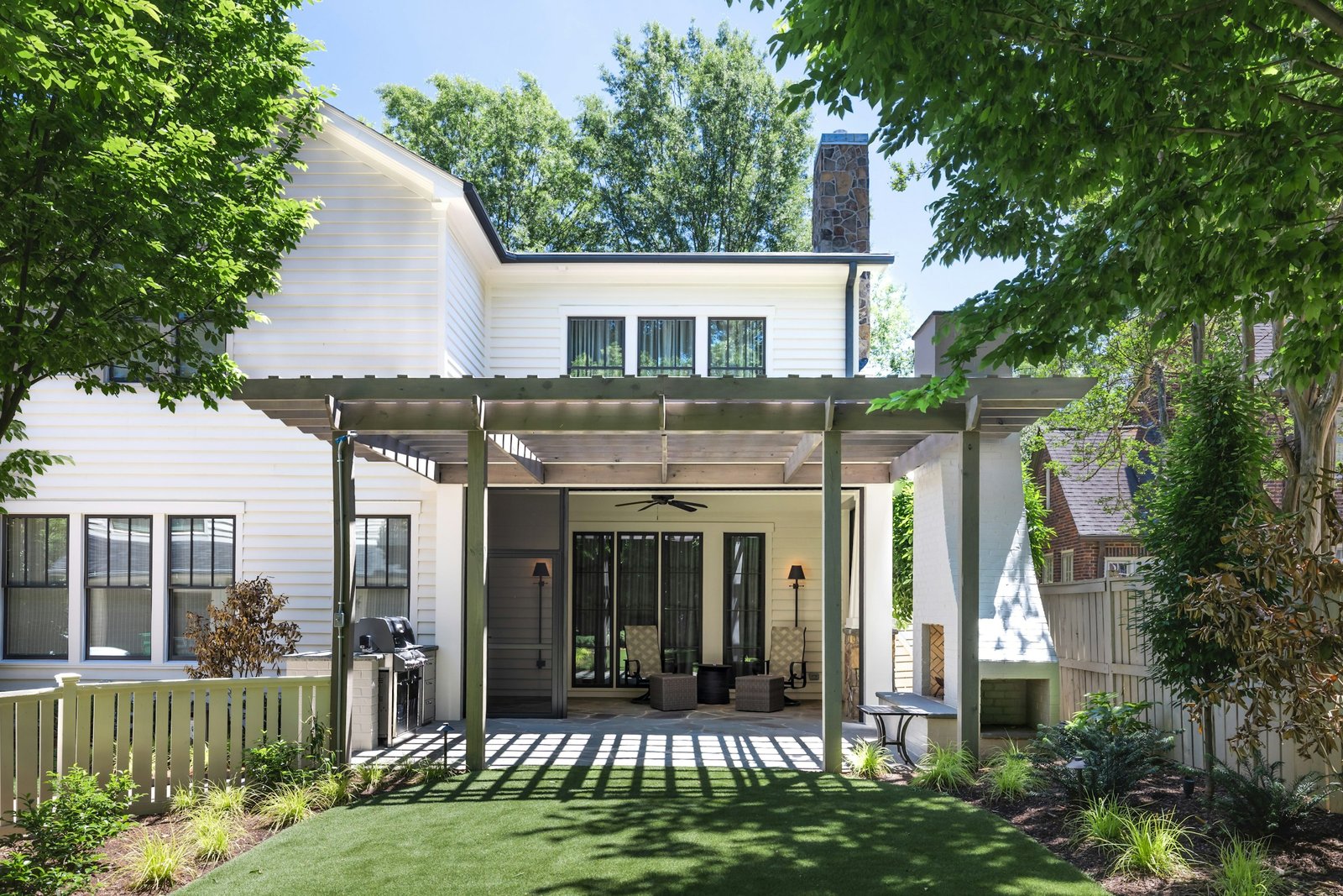 White two-story home opening onto a covered patio, planted borders and a compact lawn.
