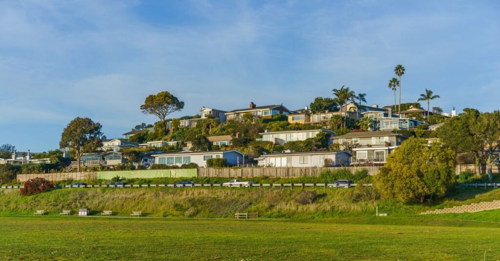 Homes and streets on a green hillside beneath a clear sky