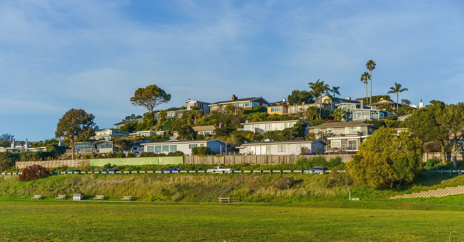 Homes and streets on a green hillside beneath a clear sky