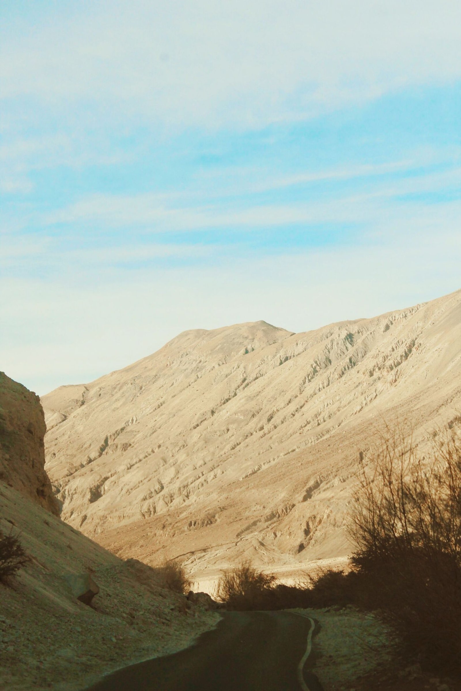 Narrow paved road winding through dry mountain terrain