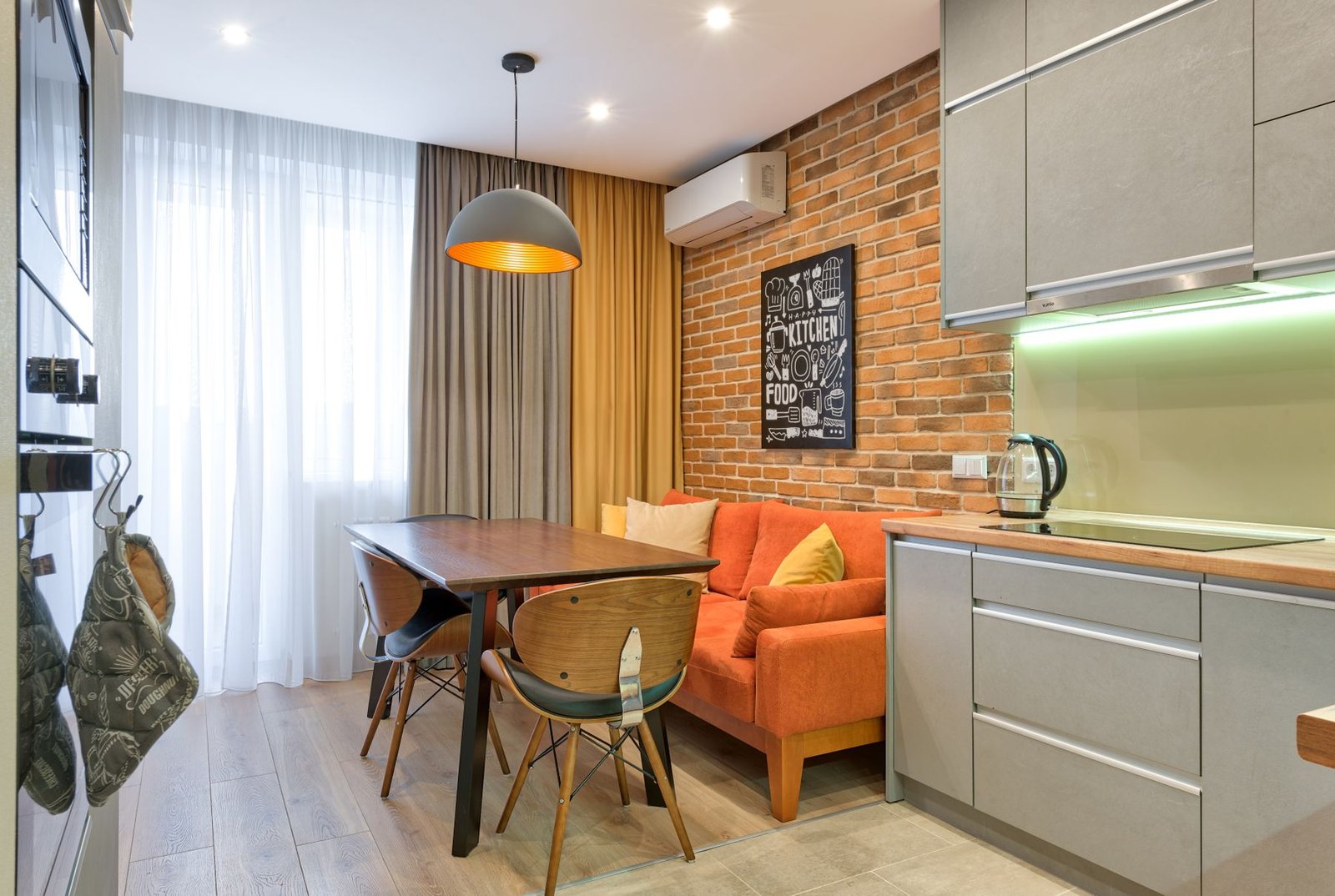 Compact open kitchen with dining table and brick wall