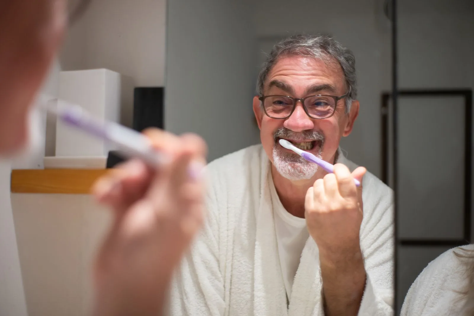 Older adult brushing teeth in a bathroom