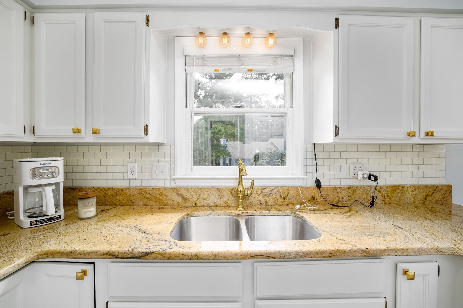 Kitchen counter, sink, gold-tone faucet and white cabinetry.