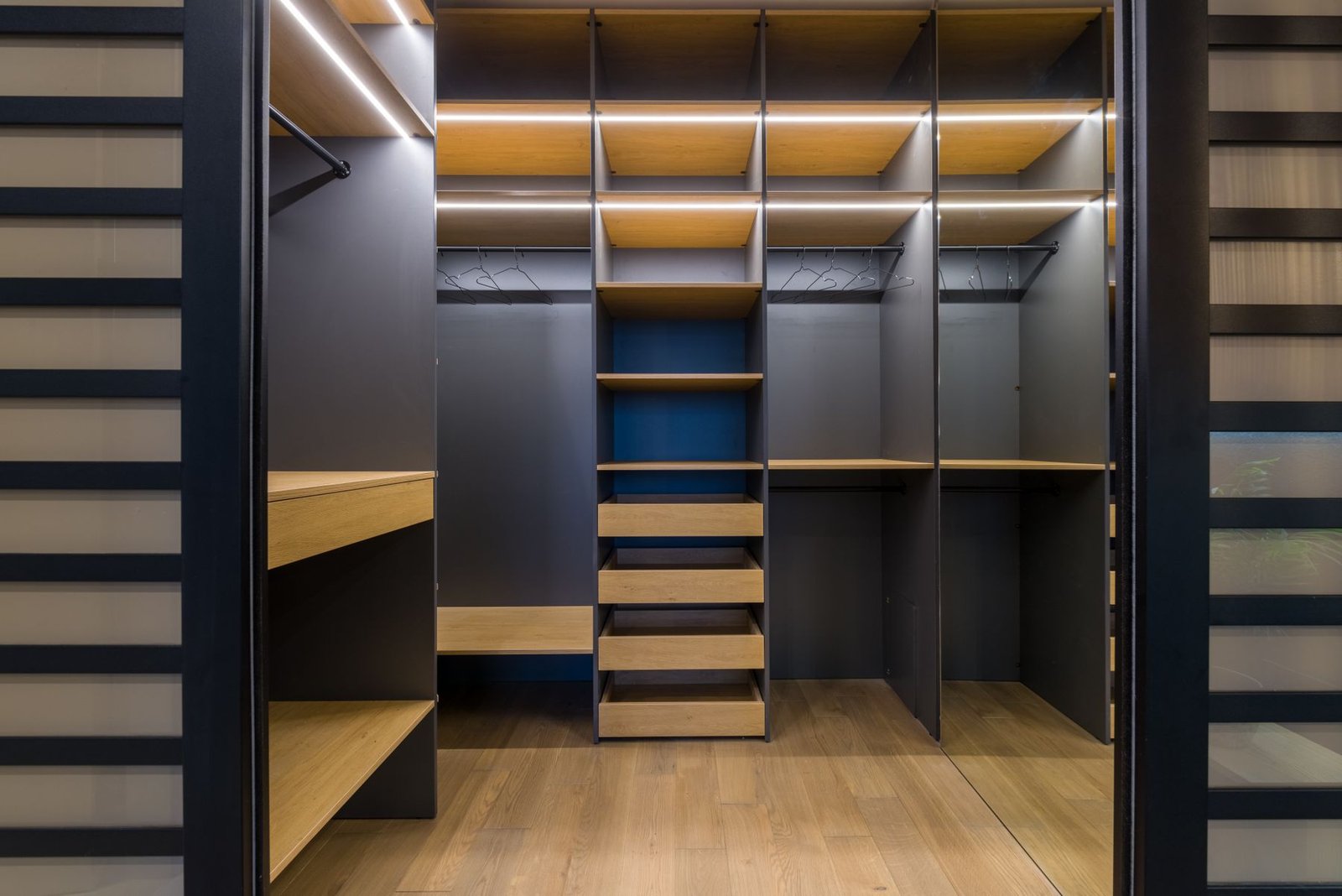 Empty fitted closet with open shelves, drawers, hanging rails and strip lighting