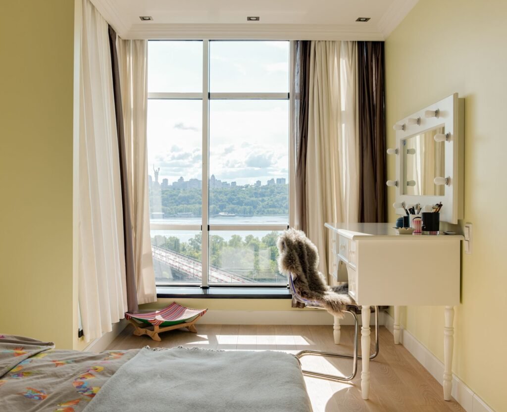 Bedroom with daylight, a bed and a dressing table beside the windows.