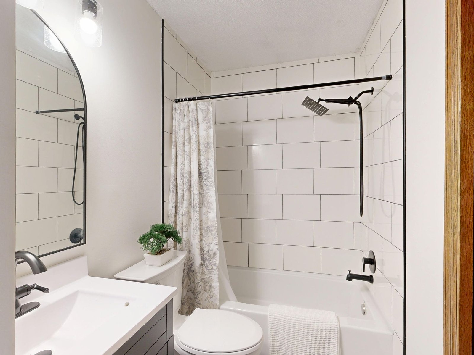 Compact bathroom with a white vanity, toilet and tiled tub and shower