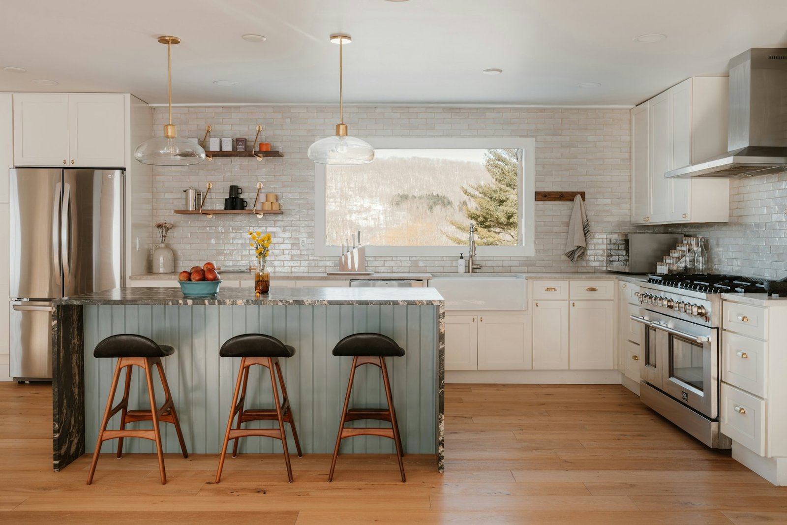 White kitchen with island, stools and a large window