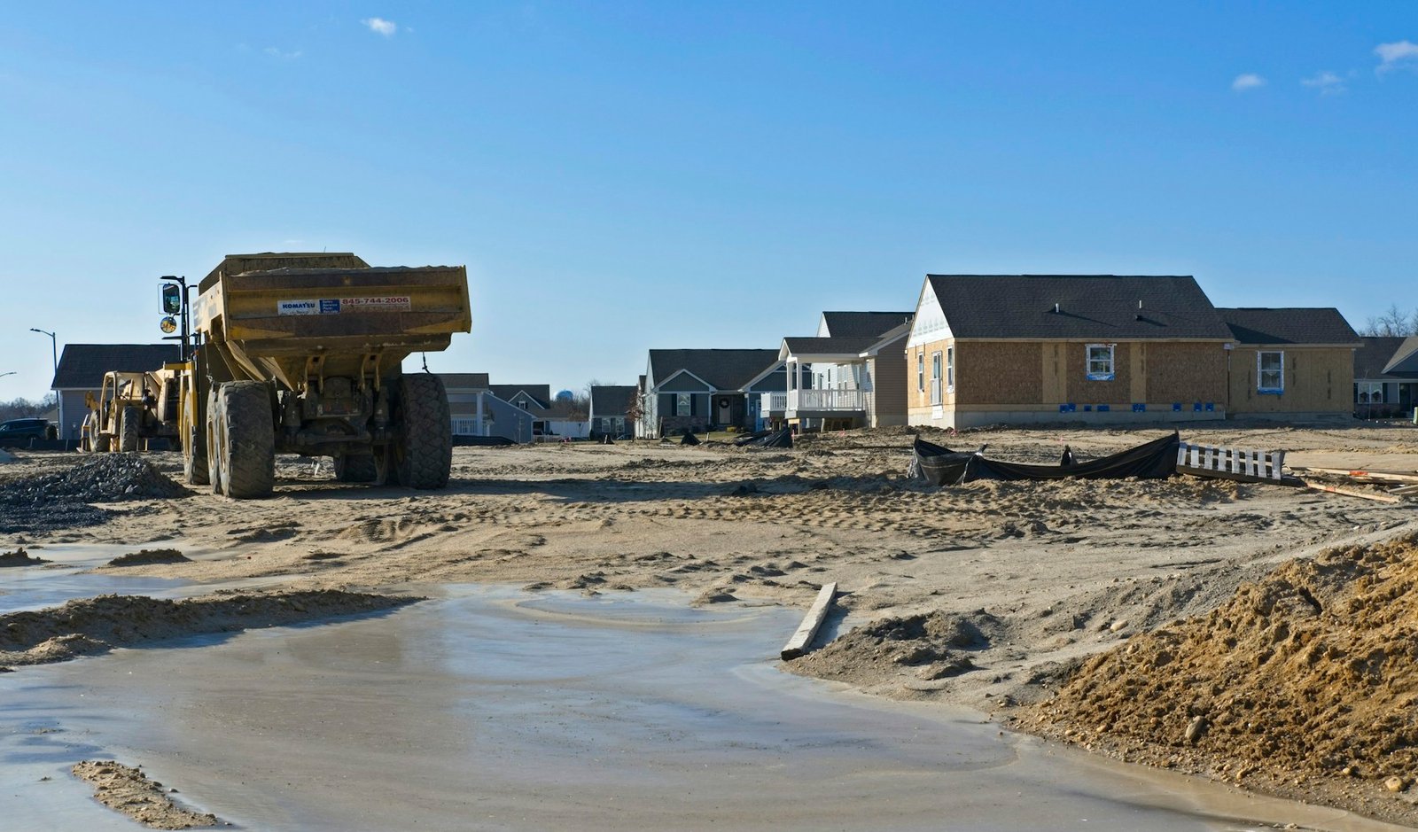 Empty residential construction site with earthmoving equipment and homes in the background