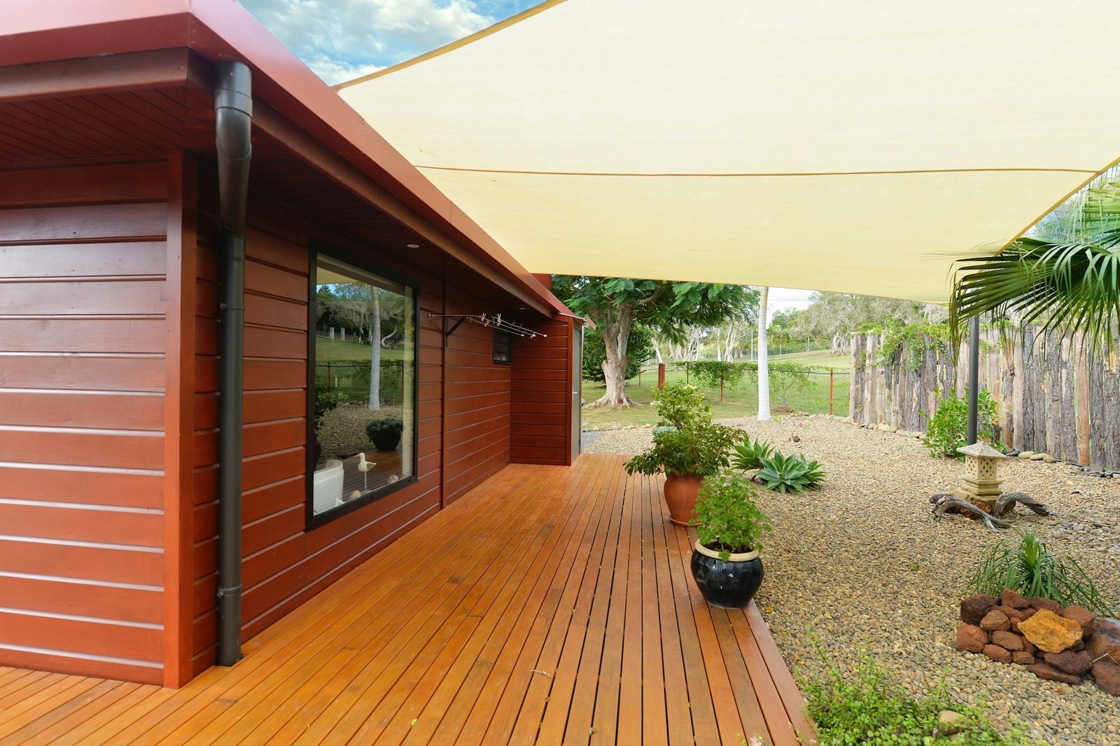 Timber-clad home opening onto a wooden deck and gravel garden