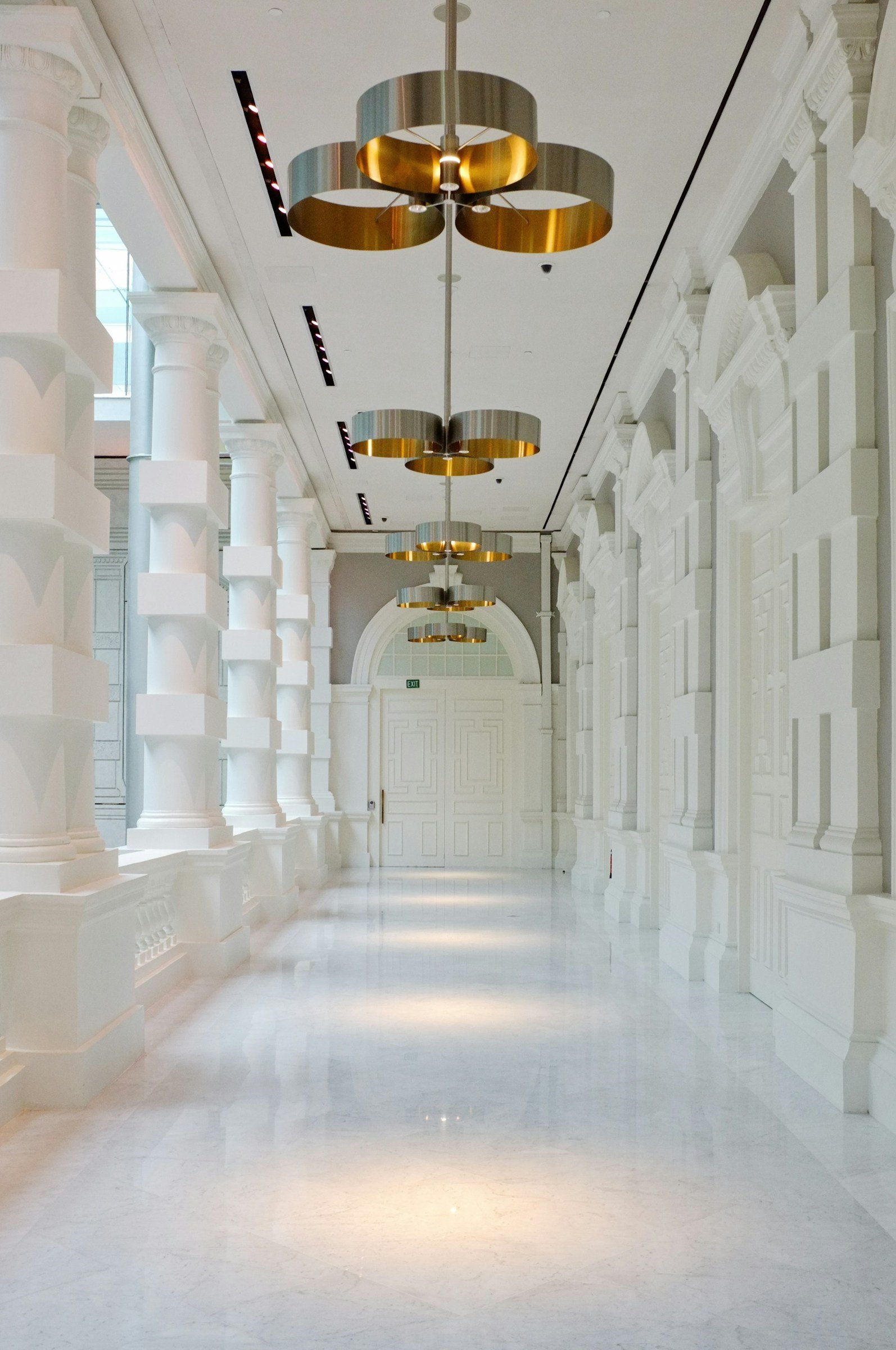 Empty corridor with columns, pendant lights and a reflective floor