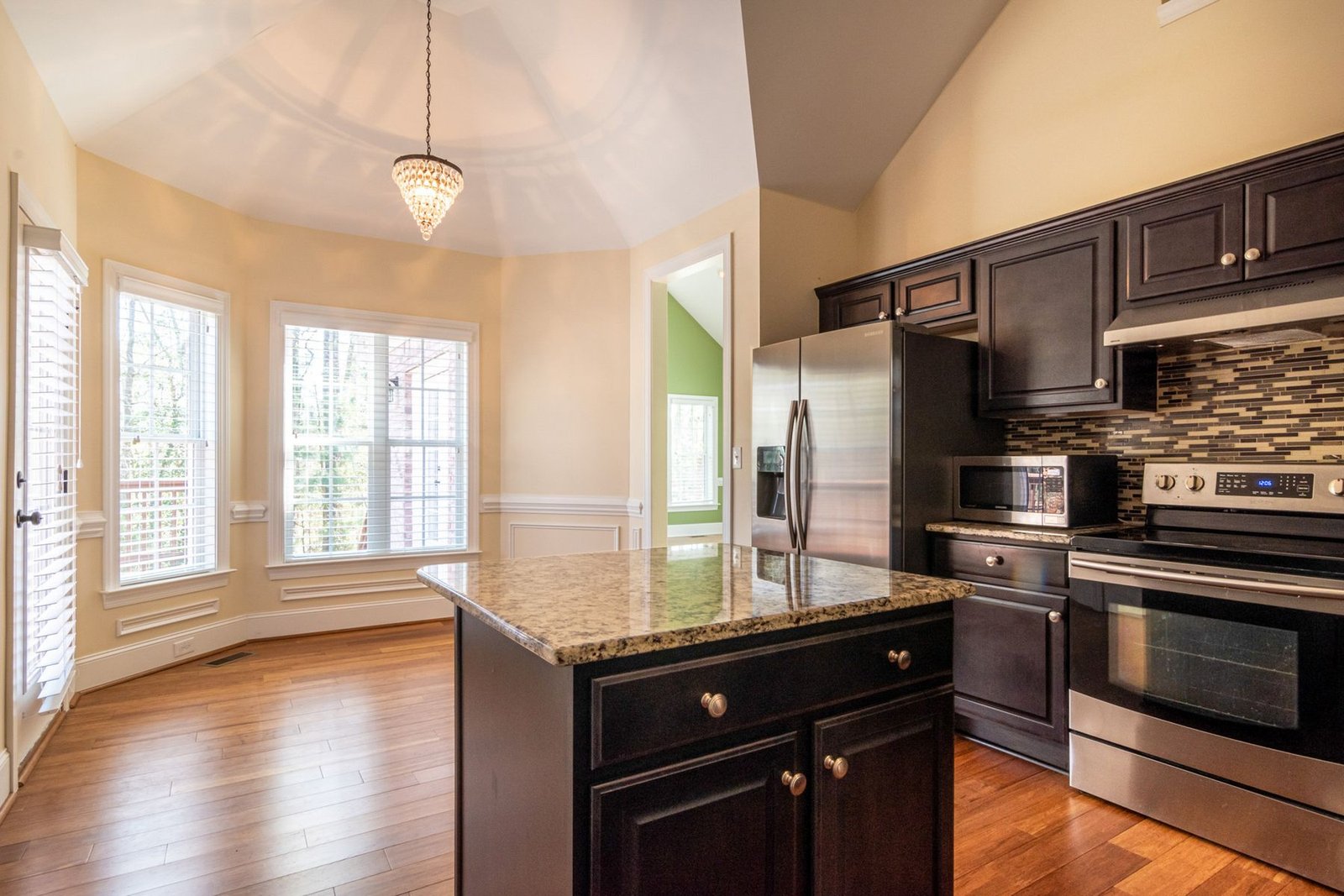 Kitchen with dark cabinets, a stone countertop island and a bright breakfast area