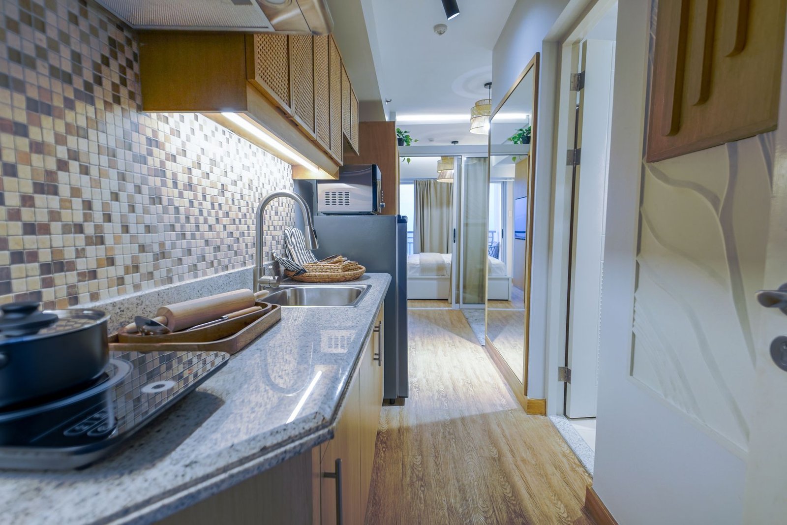 Narrow kitchen with a sink, cooktop and a view toward a sleeping area