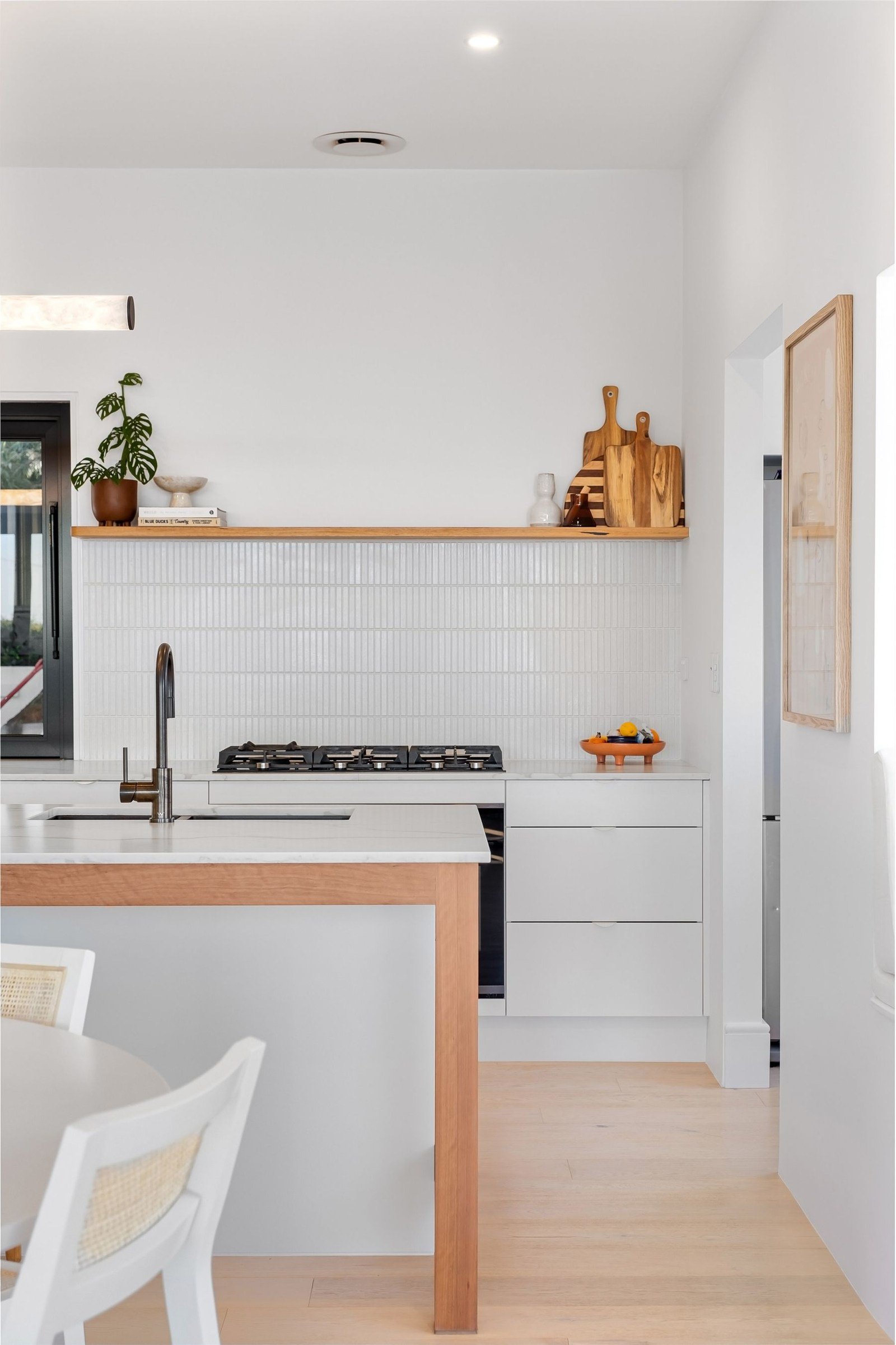 White kitchen with a wood-edged island, sink and rear counter