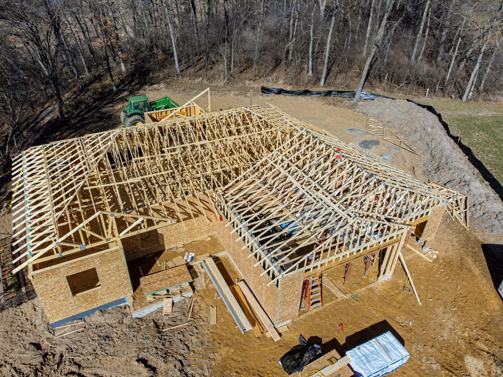 Aerial view of a house with lumber studs, roof trusses and wood sheathing.
