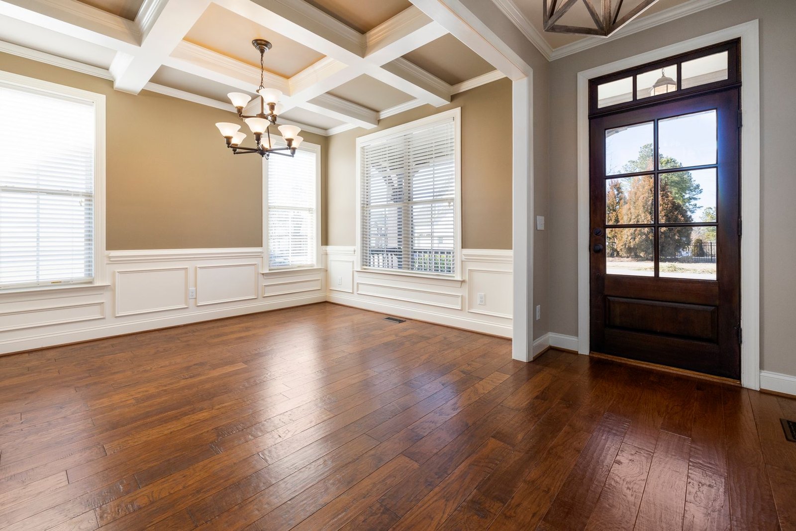 Empty finished room with wood flooring, paneled trim and a glazed front door