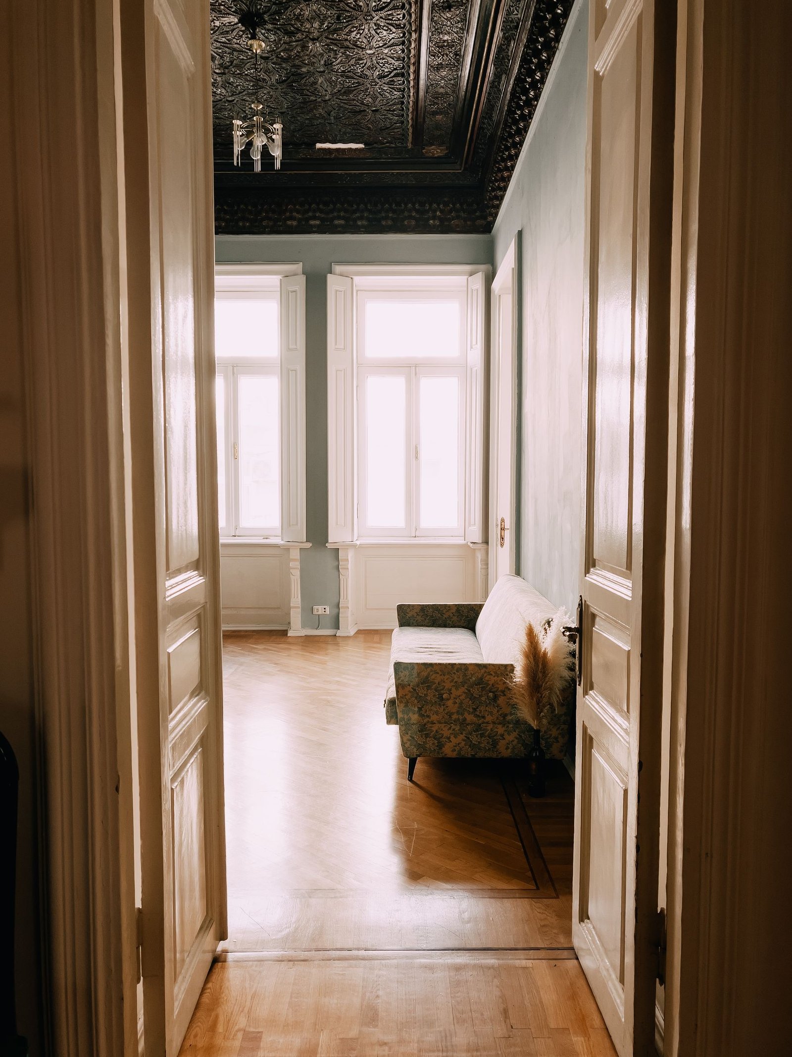View through open timber double doors into a bright room with wood flooring