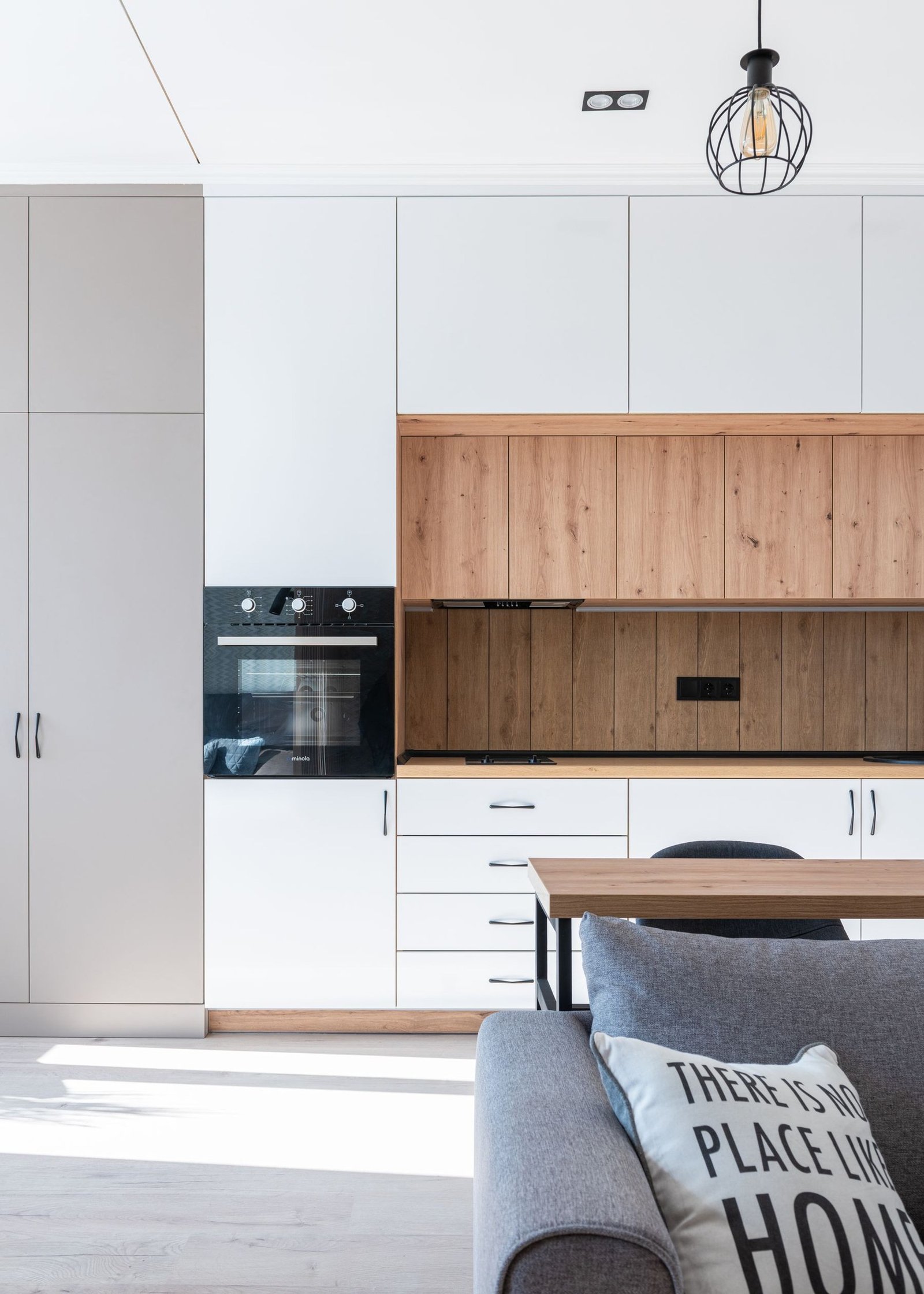 Compact living area next to a kitchen wall with cabinets and appliances.