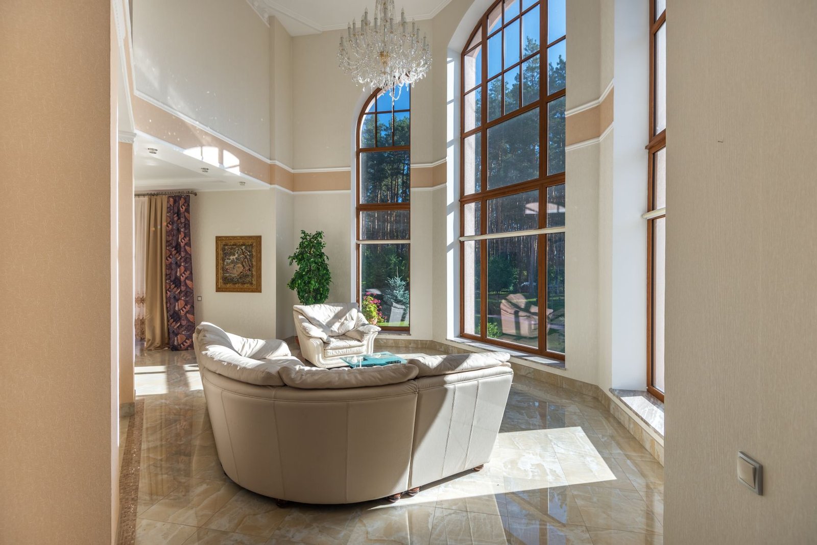 Bright living room with large windows, a chandelier and pale seating.