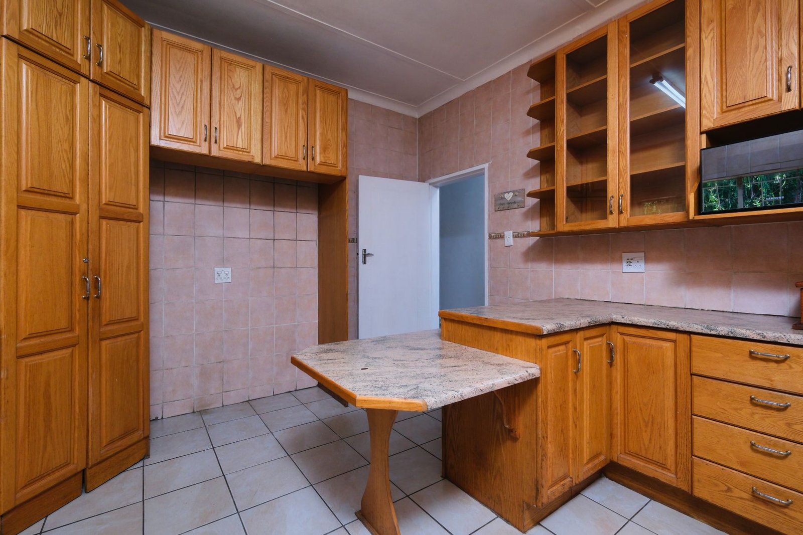 Kitchen with wood cabinets, patterned wall tile and an empty appliance recess.
