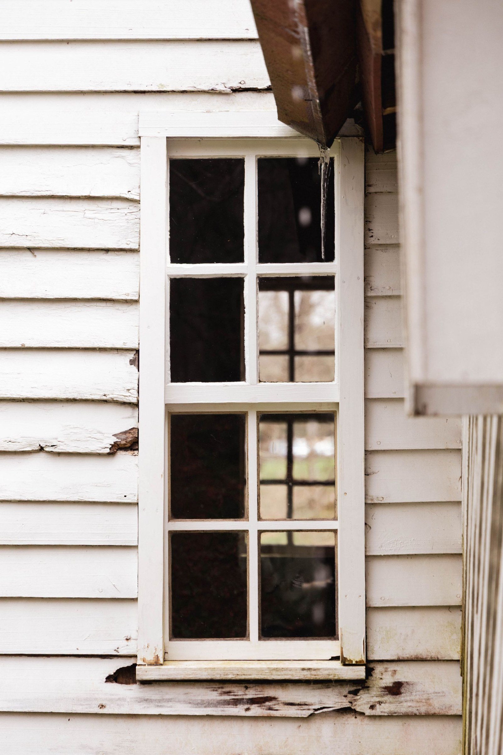 Older white wood window and painted wood clapboard siding.