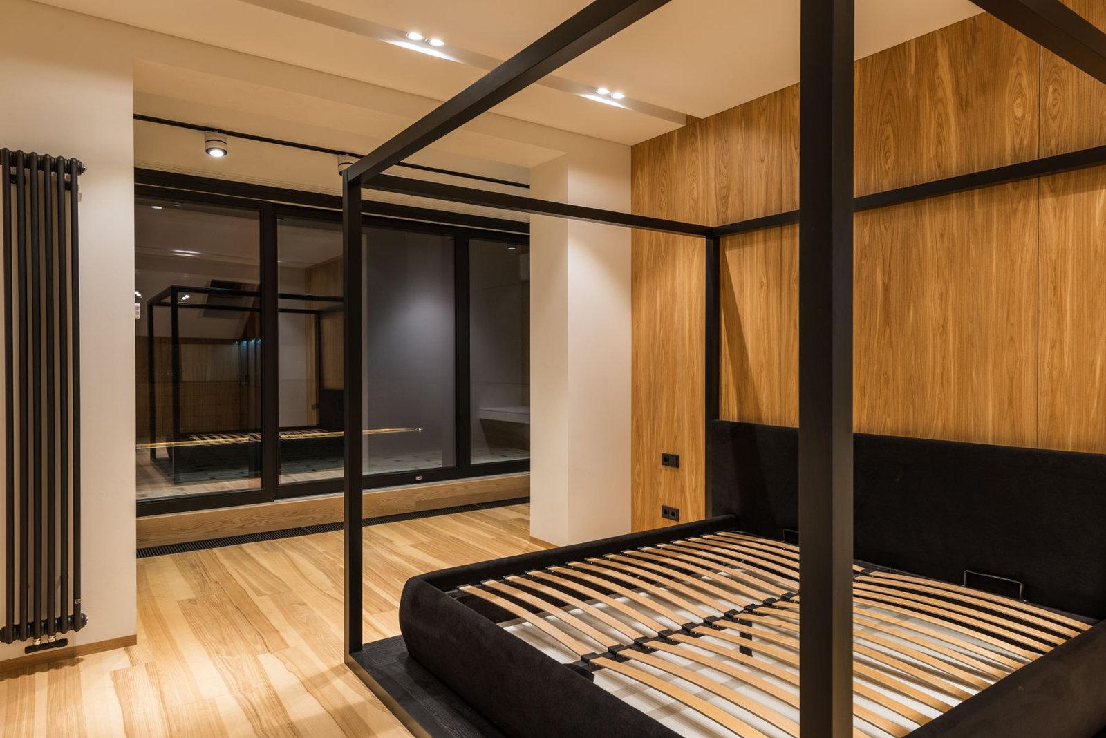 Finished bedroom with wood flooring, wood wall finishes and a canopy bed.