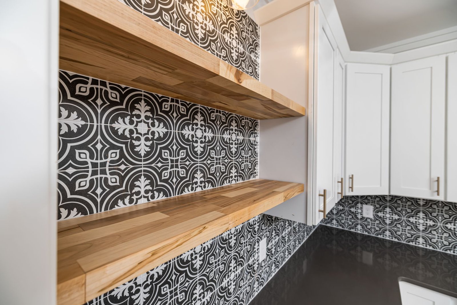 Kitchen with open wood shelves, patterned tile and white cabinets.