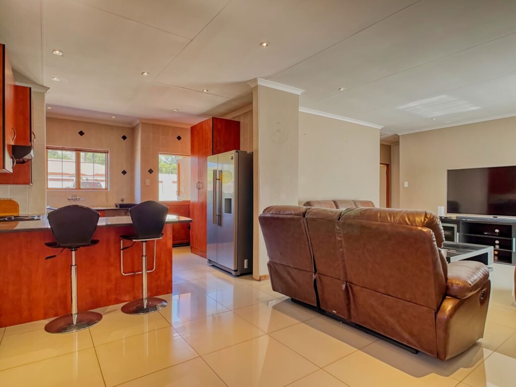 Open living and kitchen area with a brown sofa and television.