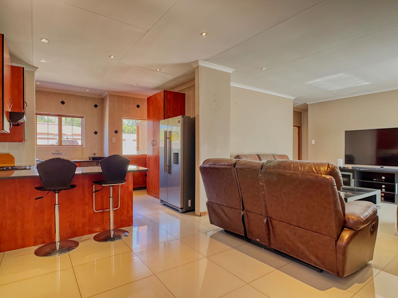 Open living and kitchen area with a brown sofa and television.