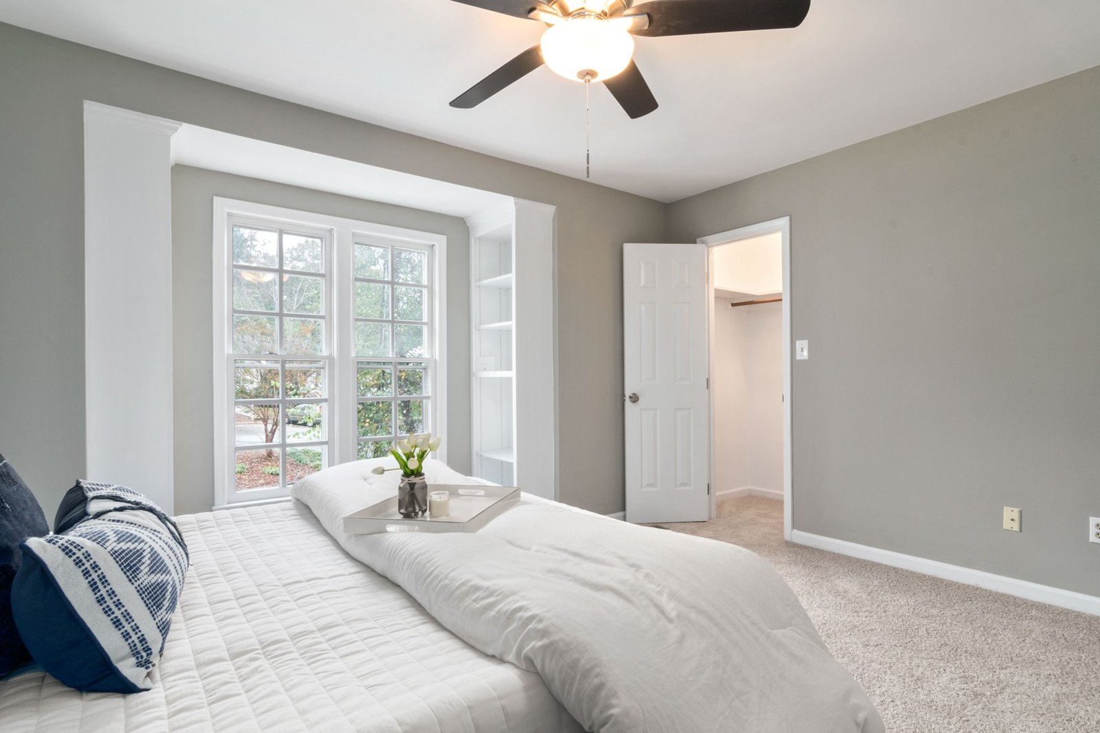 Bedroom with a large window, bed and open closet door