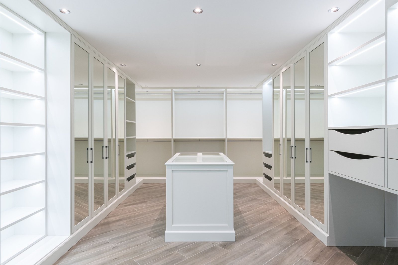 Walk-in closet with mirrored doors, drawers, open shelves and a central island