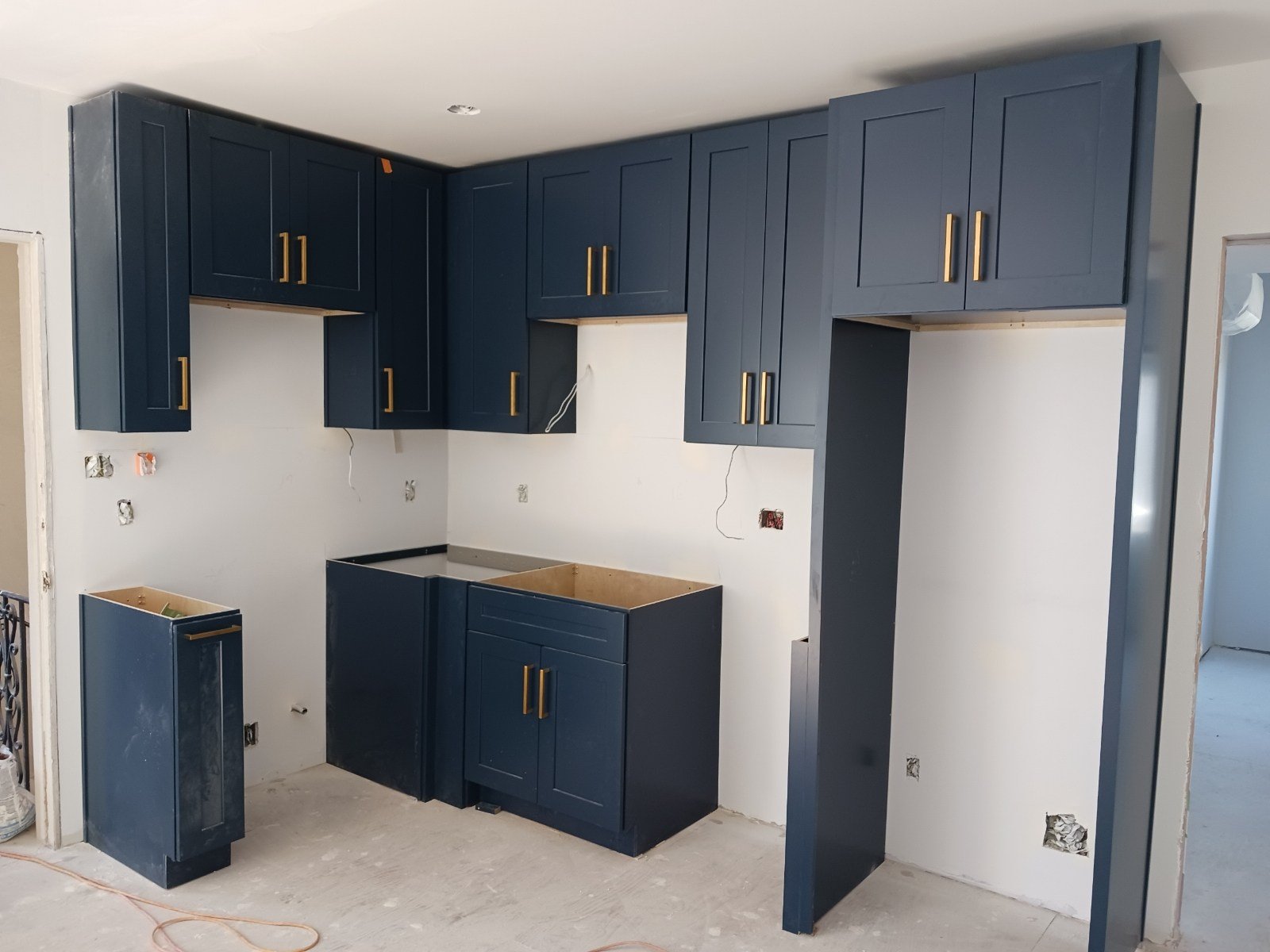 Blue kitchen cabinets during installation with unfinished counter areas and exposed electrical points