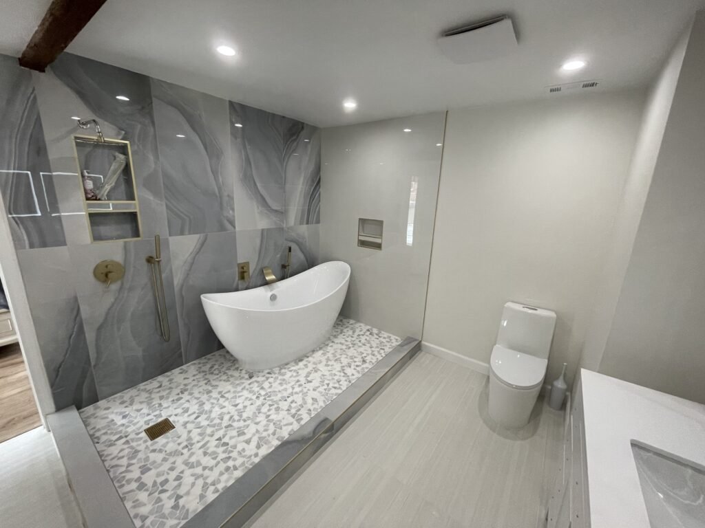 White freestanding tub beside a large tiled shower with recessed ceiling lights and a white ceiling grille