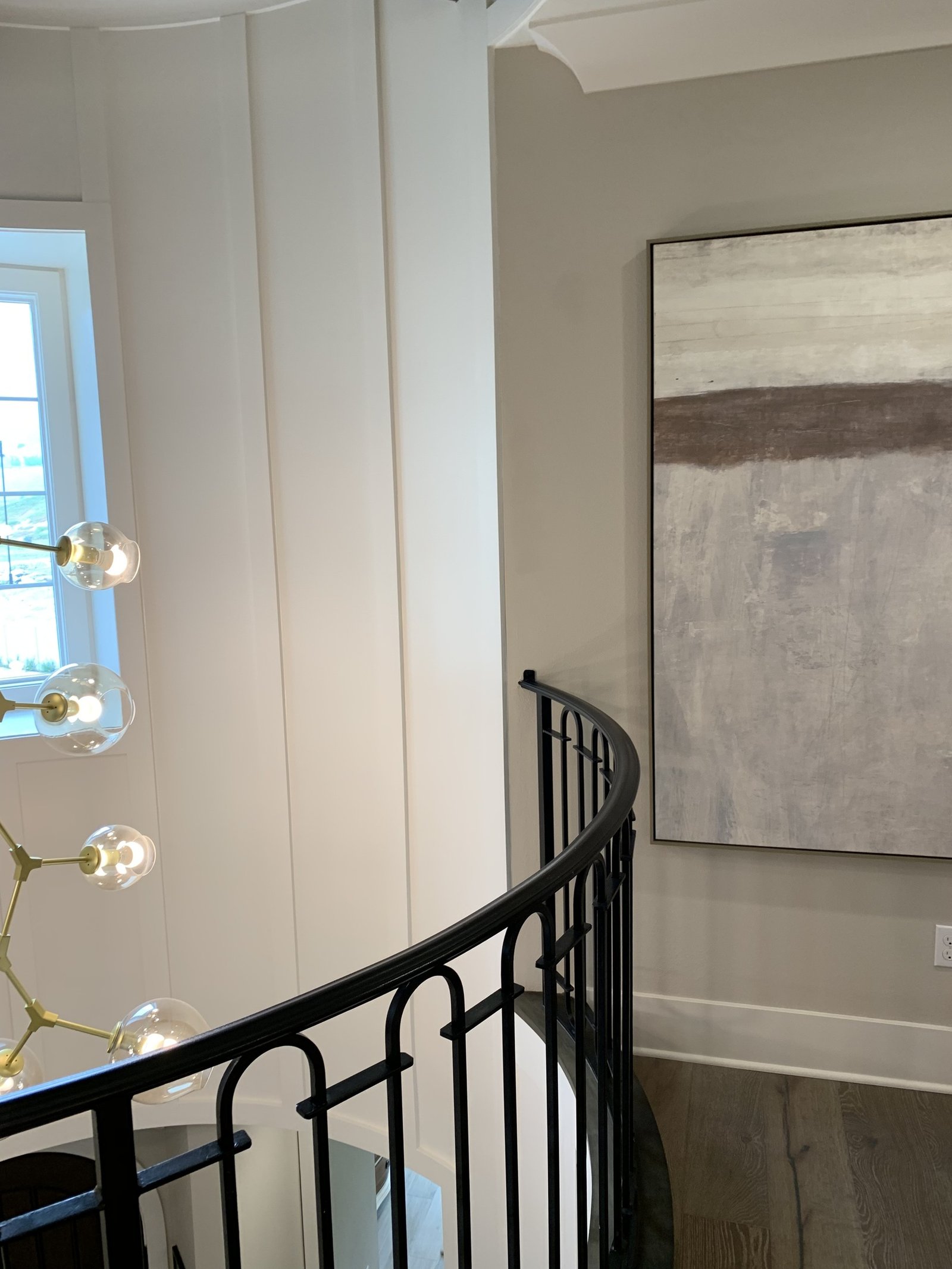 Finished upper stair landing with a dark curved guard, tall window and pendant light