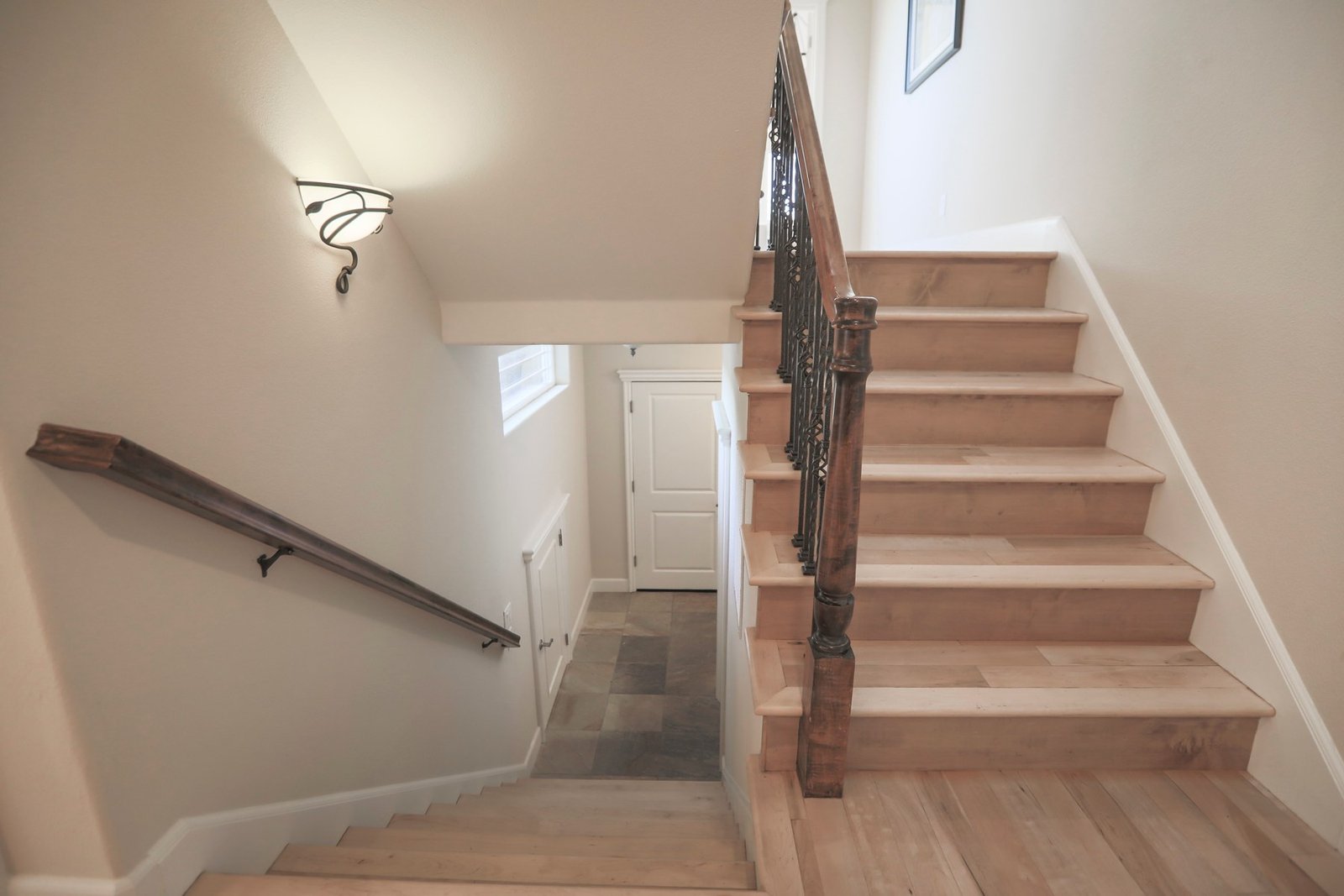 Wooden staircase rising beside another flight descending toward a closed door