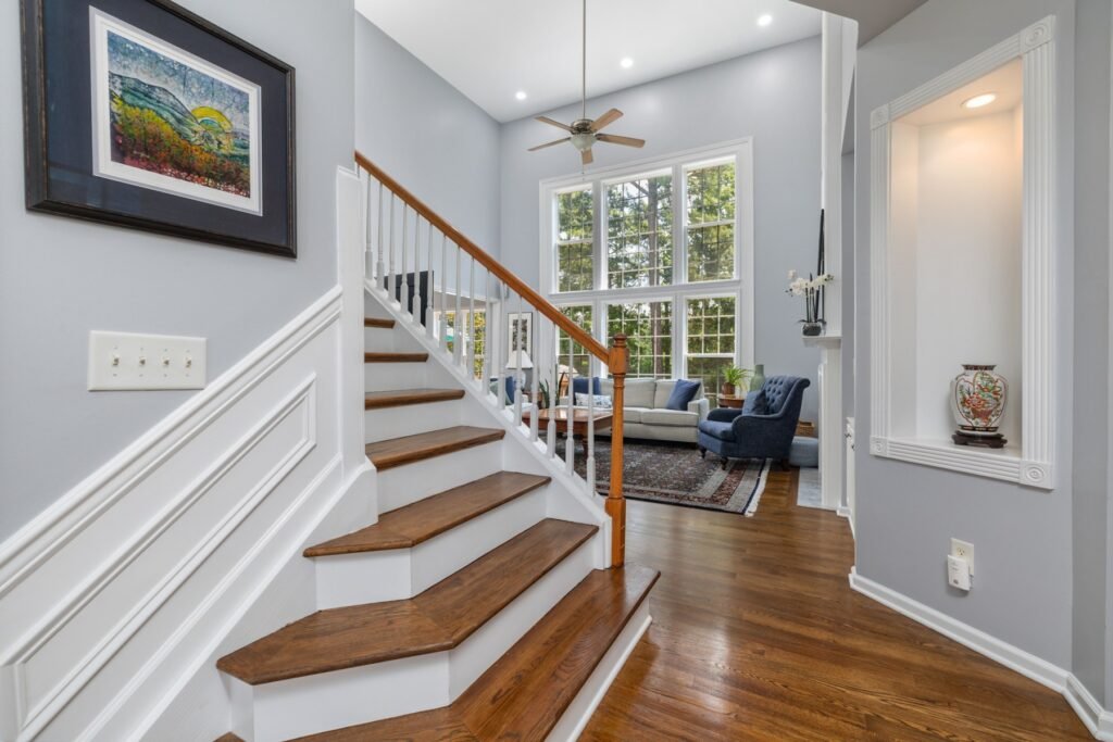 Wooden staircase beside an entry hall leading into a bright living room
