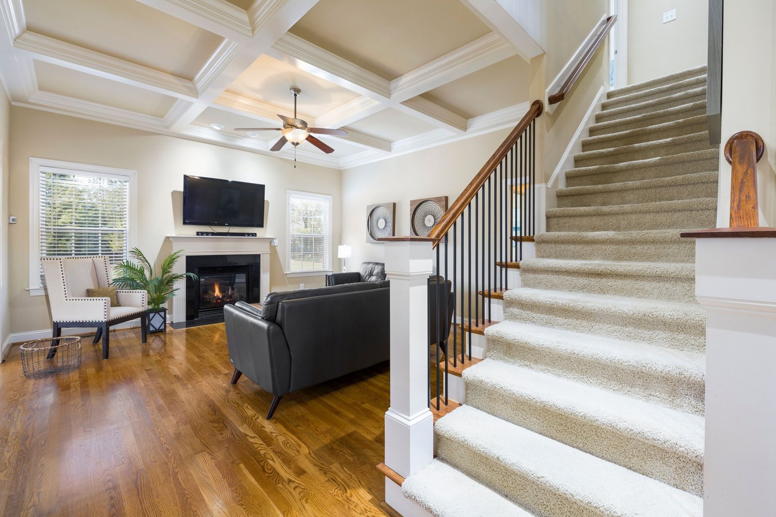 Carpeted staircase beside a furnished living room with a fireplace and windows