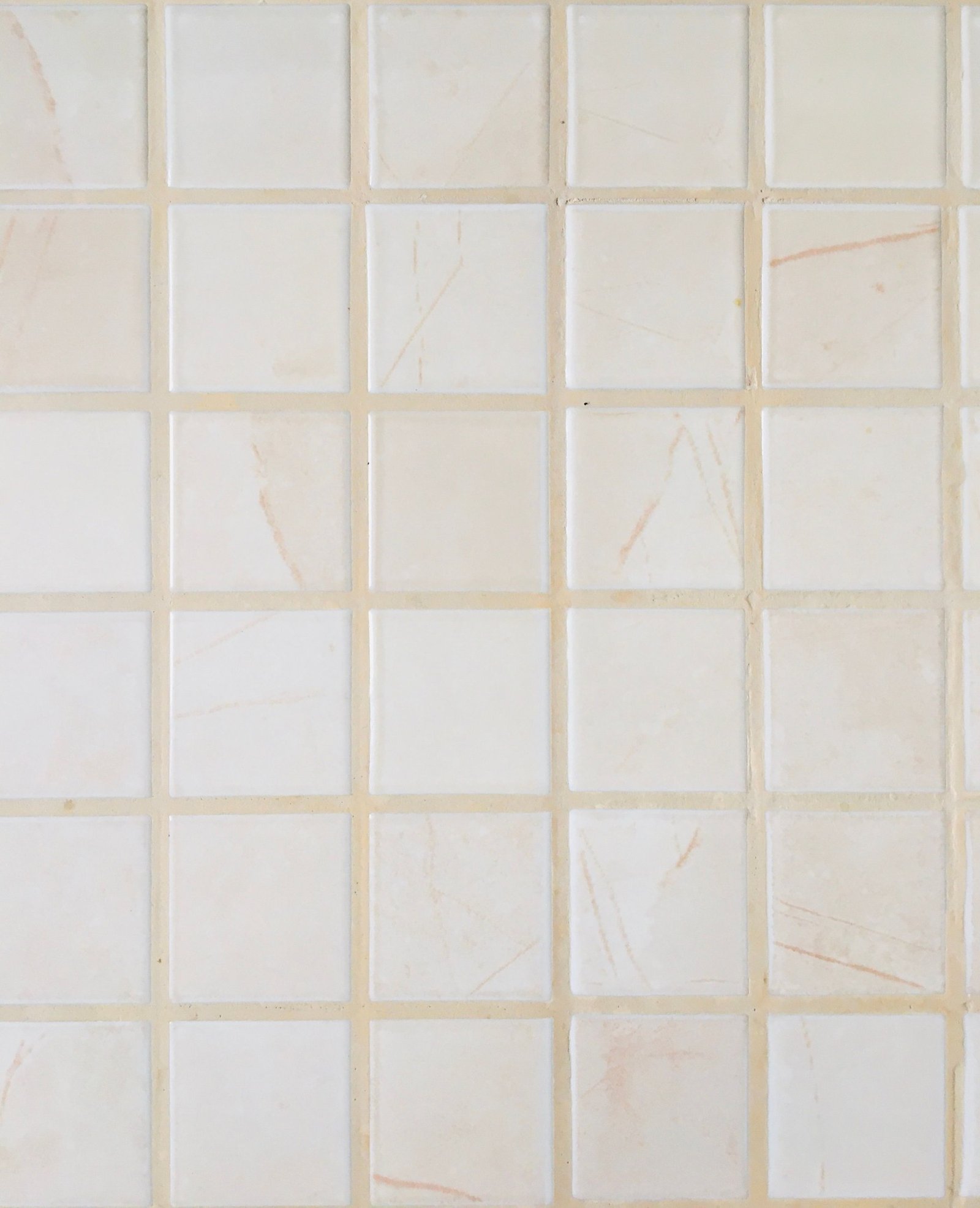Close-up of pale square tiles separated by cream-colored grout