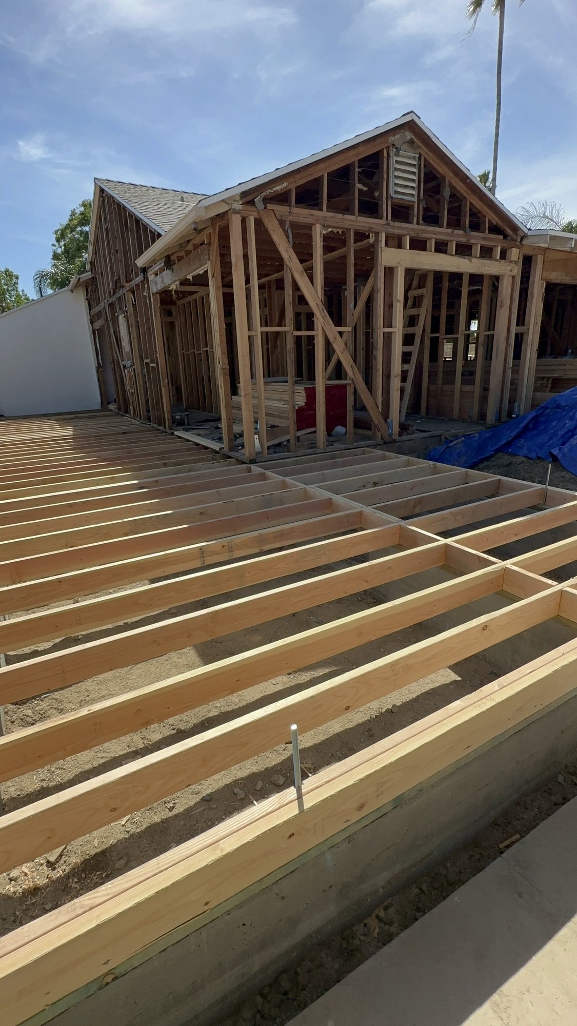 Exposed wood floor joists beside stripped wood-stud walls and a gabled roof
