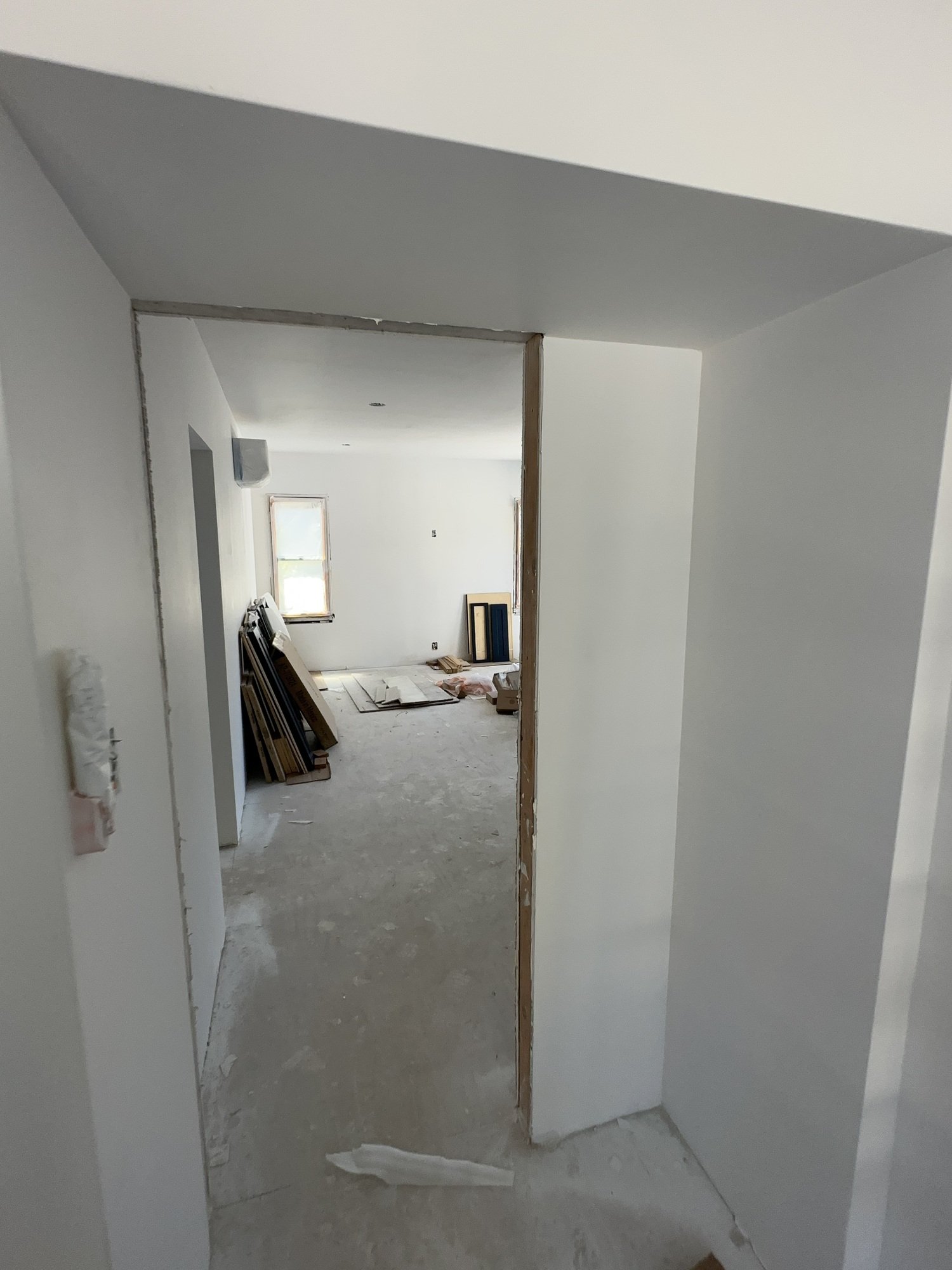 Doorway with exposed wood jamb edges, white walls and loose finishing materials in the adjoining room
