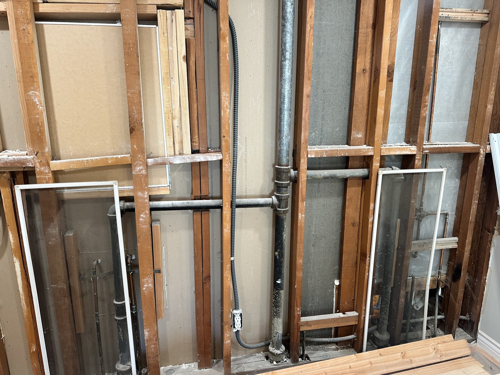 Wood-stud wall with visible piping, electrical boxes and service lines
